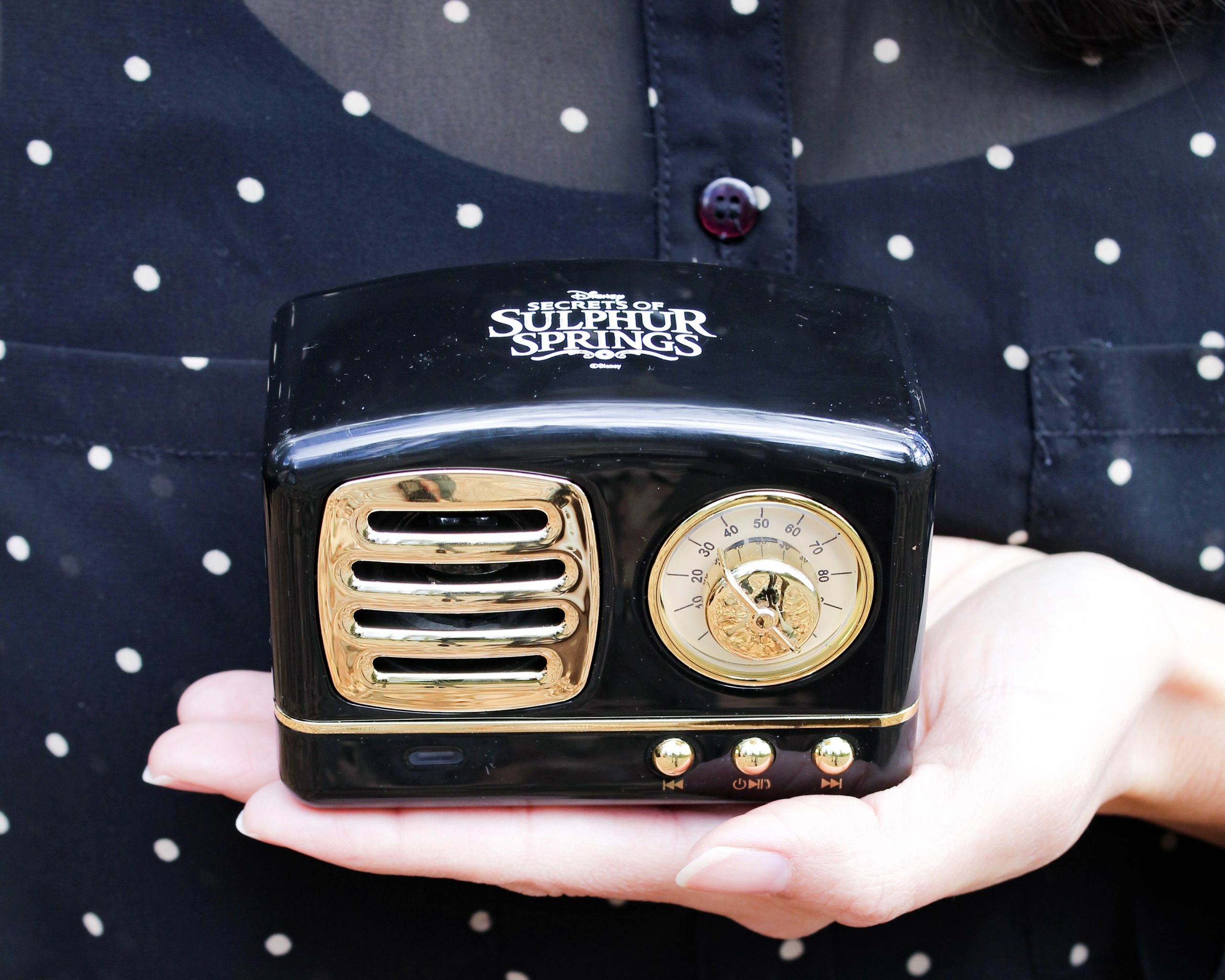 Casey holds a bluetooth speaker in the shape of a miniature replica of the time travel radio device from Disney Channel's Secrets Of Sulphur Springs