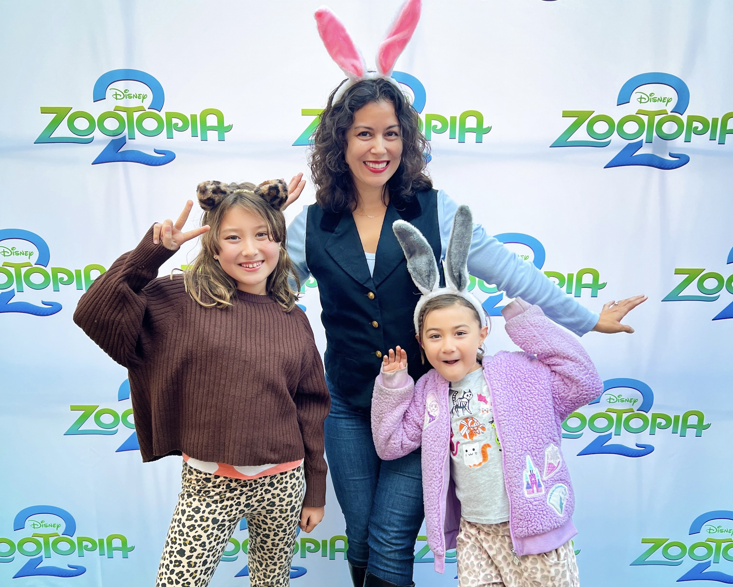 Casey Dacanay and children at an early screening of Disney’s Zootopia 2, posing in front of the official Zootopia 2 backdrop while wearing playful animal ear headbands.